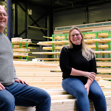Projectleider Steven en werkvoorbereider Jeanine poseren op een stapel hout