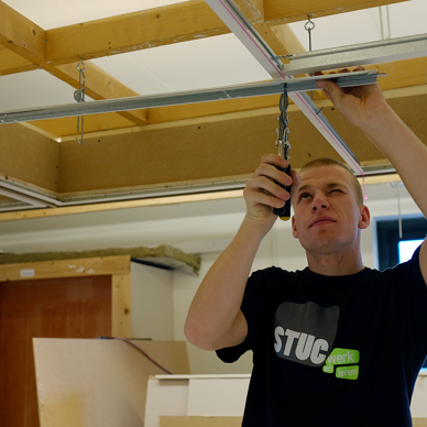 Een plafond- en wandmonteur is geconcentreerd aan het werk